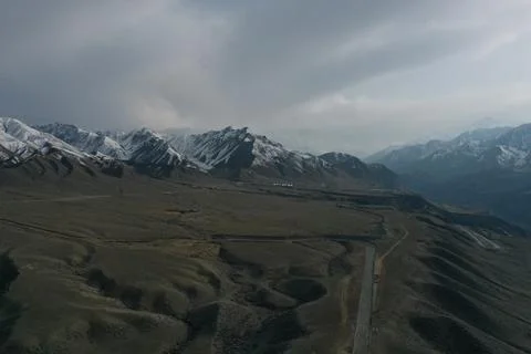 Drone View of Vast Arid Plain and Snow Mountain Range with Highway, Xinjian.. Stock Photos