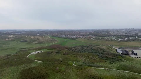 A drone view of vast green fields, sand dunes, and winding paths 스톡 동영상 299294079