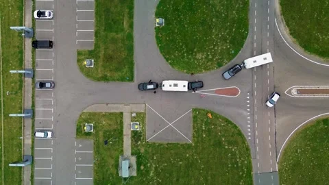 Drone view of vehicles with trailers navigating a road intersection beside Stock Footage 315702978