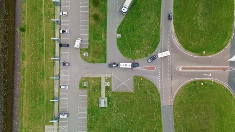 Drone view of vehicles with trailers navigating a road intersection beside Stock Footage 316764484