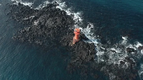 Drone view.The waves hit the volcanic stone and the red lighthouse. Jeju Island  Stock Footage 122271489