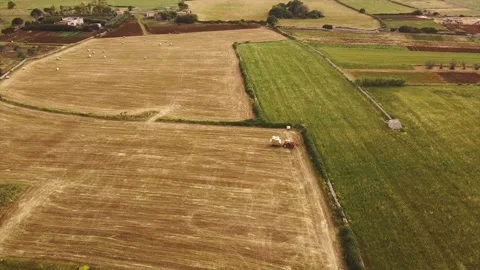 Drone view of a wheat field with tractor and hay bales Stock Footage 131194991