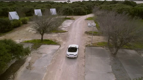 Drone view White convertible drive through a trees and wigwams Stock Footage 259974252