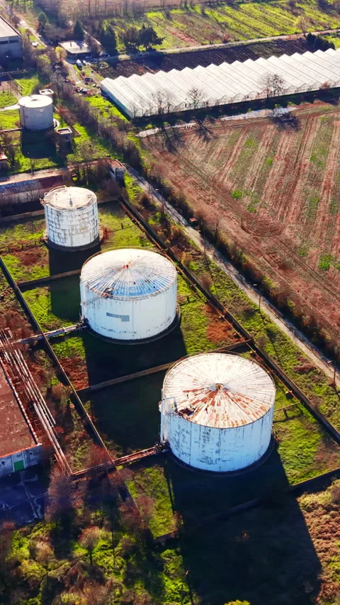 Drone view of white storage tanks beside greenhouse, Bulgaria Vertical video. Video stock 338007990