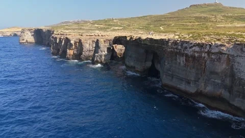 Drone view of Wied il-Mielaħ arch and cliffs along Malta's coast waters Stock Footage 341387187