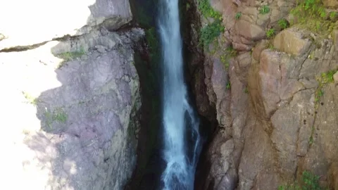 Drone view of wild cascade rushing through tight rocky fissure in Kazakhstan Видео 338116750