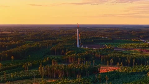Drone view of a wind turbine under construction at sunset, with crane lifting Stock-Footage 333315044