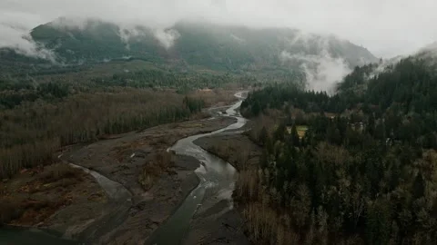 Drone View of a Winding River Valley Surrounded by Mountains on a Cloudy Day Stock Footage 315090903
