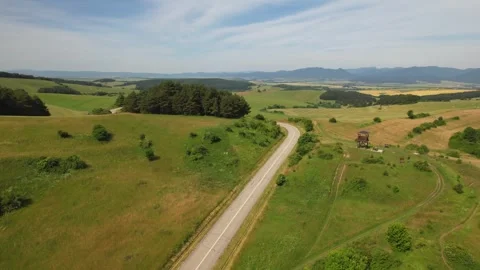 Drone view of winding road running through green fields and rolling hills Stock Footage 312005027