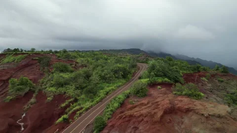 Drone view of a winding road through red soil and hills in Hawaii Stockbeeldmateriaal 347825899