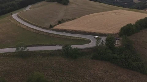 Drone view of a winding rural road curving through rolling farmland bordered by Stock Footage 339383349