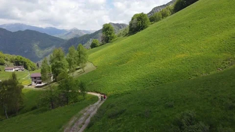 Drone view of a young couple walking along a mountain path close to green hil Stock Footage 154959605