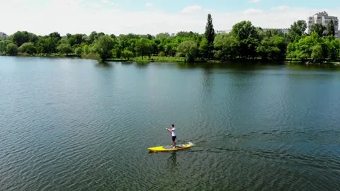 Drone view of a young guy paddling a SUP board Stock Footage 247438868