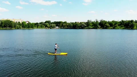 Drone view of a young guy paddling a SUP board Stock Footage 247438872
