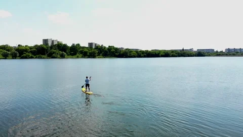 Drone view of a young guy paddling a SUP board Stock Footage 247439041