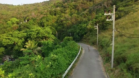 Drone view of a young man jogging on an asphalt road among tropical forests Stock Footage 209459211