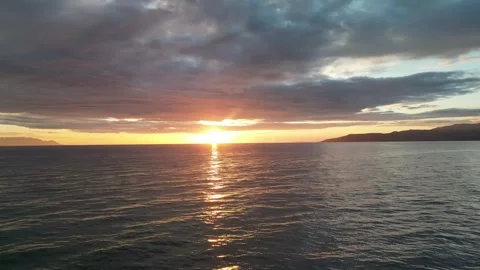 Drone watches the sun set over the gently wavy sea and moves towards the sunset Video stock 312448934