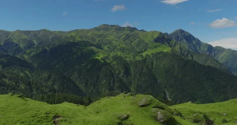Drone wide view of vibrant green pastures and rocky ridge overlooking mountain Vídeos de archivo 346340525
