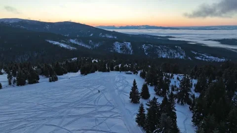 Drone winter orbit around snowboarder silhouette before sunrise Stock Footage 336445872