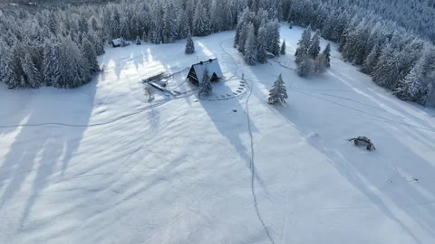 Drone winter orbit tracking wooden mountain refuge on snowy meadow Stock Footage 336384514