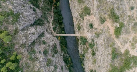 Drone zenith descent to deep ravine and to the bottom suspension bridge Stock Footage 124387305