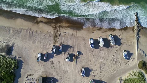 Drone zooming in over sandy beach with fishing boats docked on the beach Stock Footage 305565798