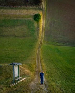 Droneception image showing a man watching along a long way between the field to 库存照片