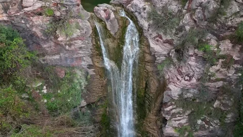 The drone's camera descends following the flow of a waterfall among rocky rocks Stock Footage 263442659