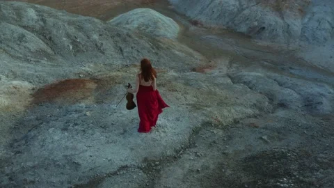 Drone's camera is flying by girl in a red dress with long red hair running with  Stock Footage 222545845