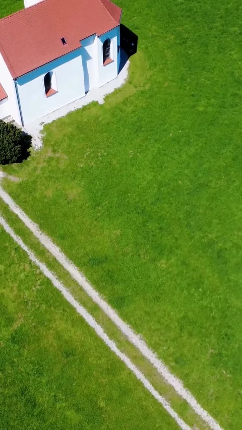 Drones Capture a Serene Landscape Featuring Lush Green Fields and a Quaint 動画素材 311112077