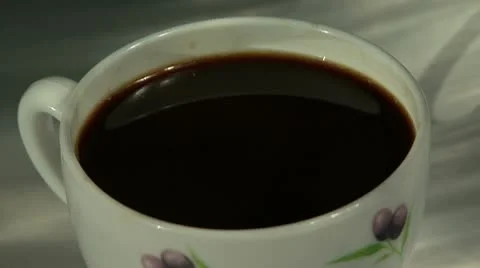 A drop of black coffee slowly drips into a full white cup Video stock 10775513