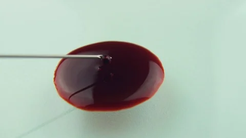 Drop of blood from sterile hypodermic needle poured onto glass surface Slowly Stock Footage