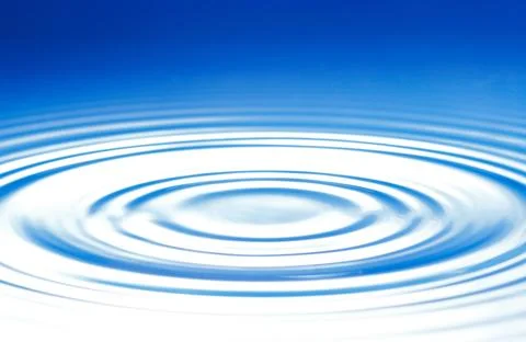 A drop causes circular waves on the water surface Stock Photos