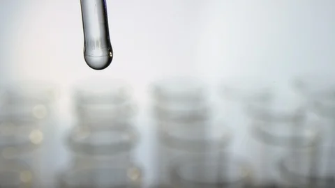 Drop of chemicals drops slowly into a test tube in front of a row of test tub Video stock 100559484