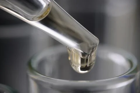 Drop of clear liquid drips into test tube on measuring tube closeup Stock Photos