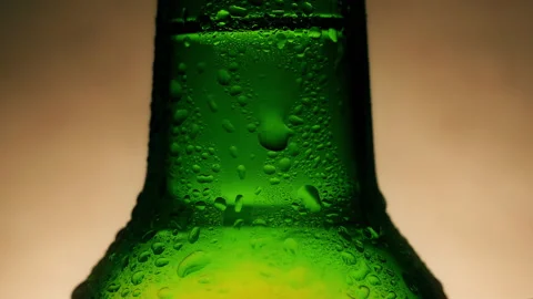 Drop of condensate drains on a green bottle of beer Stock Footage 144321759