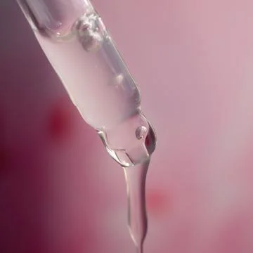 A drop of cosmetic aromatic oil drips from the pipette. Front view. Foto stock