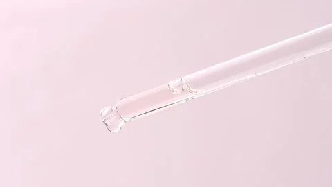 A drop of cosmetic product slowly flows from the glass dropper and falls. Stock Footage