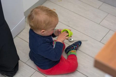 Drop down view of a child sitting on tile floor playing. Stock Photos