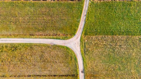 Drop down view of dirt road T-junction surrounded with fields. Stock Photos