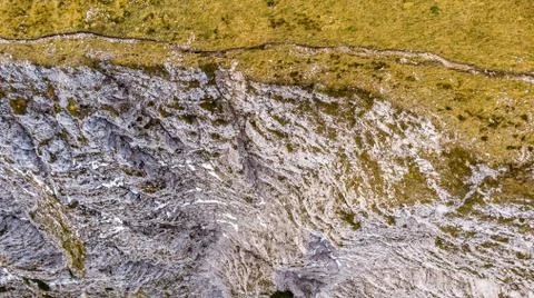 Drop down view of mountain ridge with grass covered slope on one side and sheer Stock Photos
