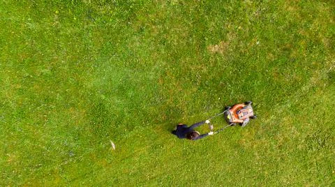 Drop down view of a person mowing lawn. 写真素材