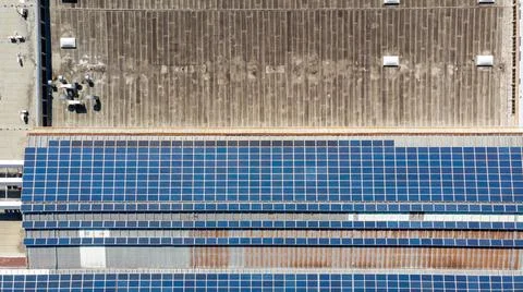 Drop down view of solar power plant with panels placed on industrial roof tops. Stock Photos