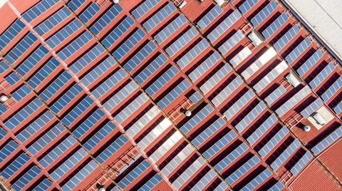 Drop down view of solar power plant with panels placed on industrial roof tops. Stock Photos