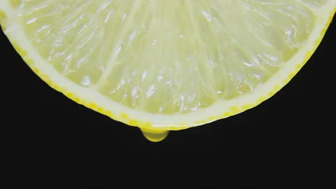 The Drop Drains Slowly From Slice Of Lemon. Macro Shot Against Black Background Stock Footage 116623039