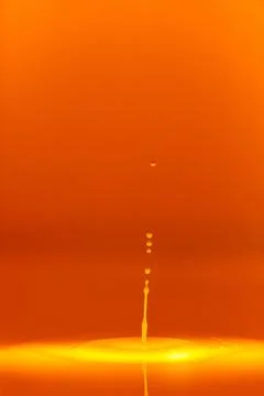 The drop falls into a dense liquid with an orange background. Abstract colo.. Foto stock