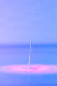 A drop falls into a thick liquid with a blue-pink background. Abstract colorful Stock Photos