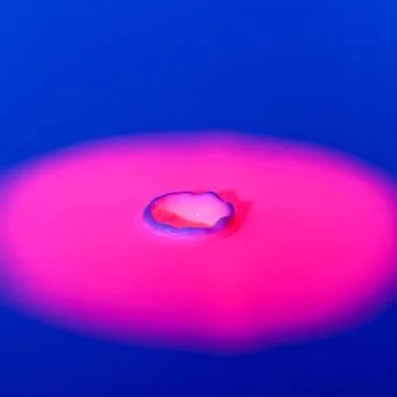 A drop falls into a thick liquid with a blue-pink background. Abstract colorful Stock Photos