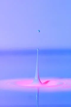 A drop falls into a thick liquid with a blue-pink background. Abstract colo.. Stock Photos