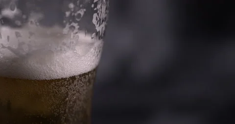 Drop flows down a perspiring glassful with beer on a black background Stock Footage 130359691